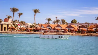 A boat traveling down a river next to a beach